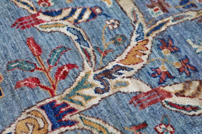 Handwoven Tree of Life rug with intricate floral and animal motifs on a blue background