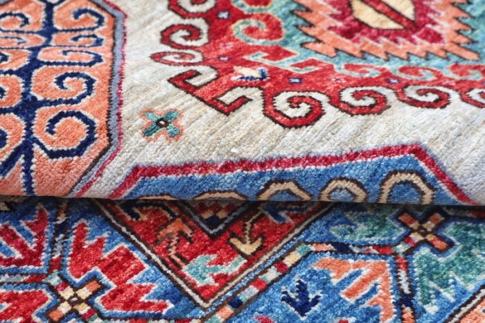 "5x7 handmade wool Kazak rug with geometric medallions in sky blue, rust red, and ivory