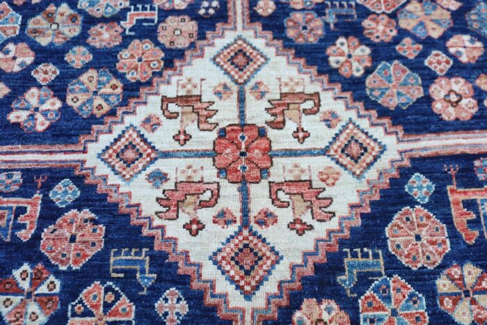 5x7 handmade Persian Shiraz wool rug with deep navy blue, ivory medallions, and tribal motifs