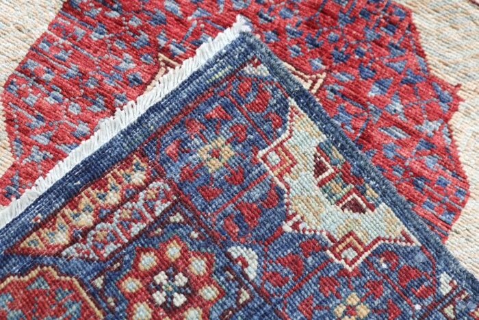 Long Persian-style runner rug with intricate tribal motifs in navy blue, red, and ivory