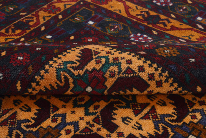 Handwoven Afghan Baluchi rug with a dark background and detailed tribal motifs in orange, red, and beige. 6'5 x 4'2 ft wool rug."