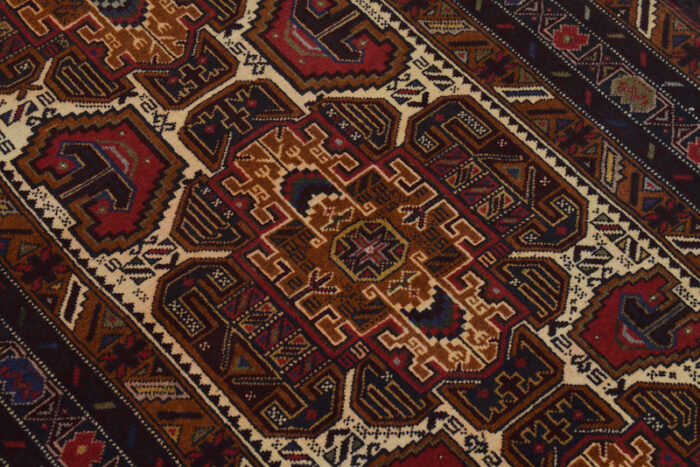 Traditional village-made Baluchi rug featuring rich red, navy, and golden accents. Handmade wool carpet measuring 6'5 x 3'3 ft."