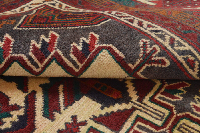 Authentic Afghan Baluch rug with a bold medallion and intricate border designs in ivory, black, and burgundy."